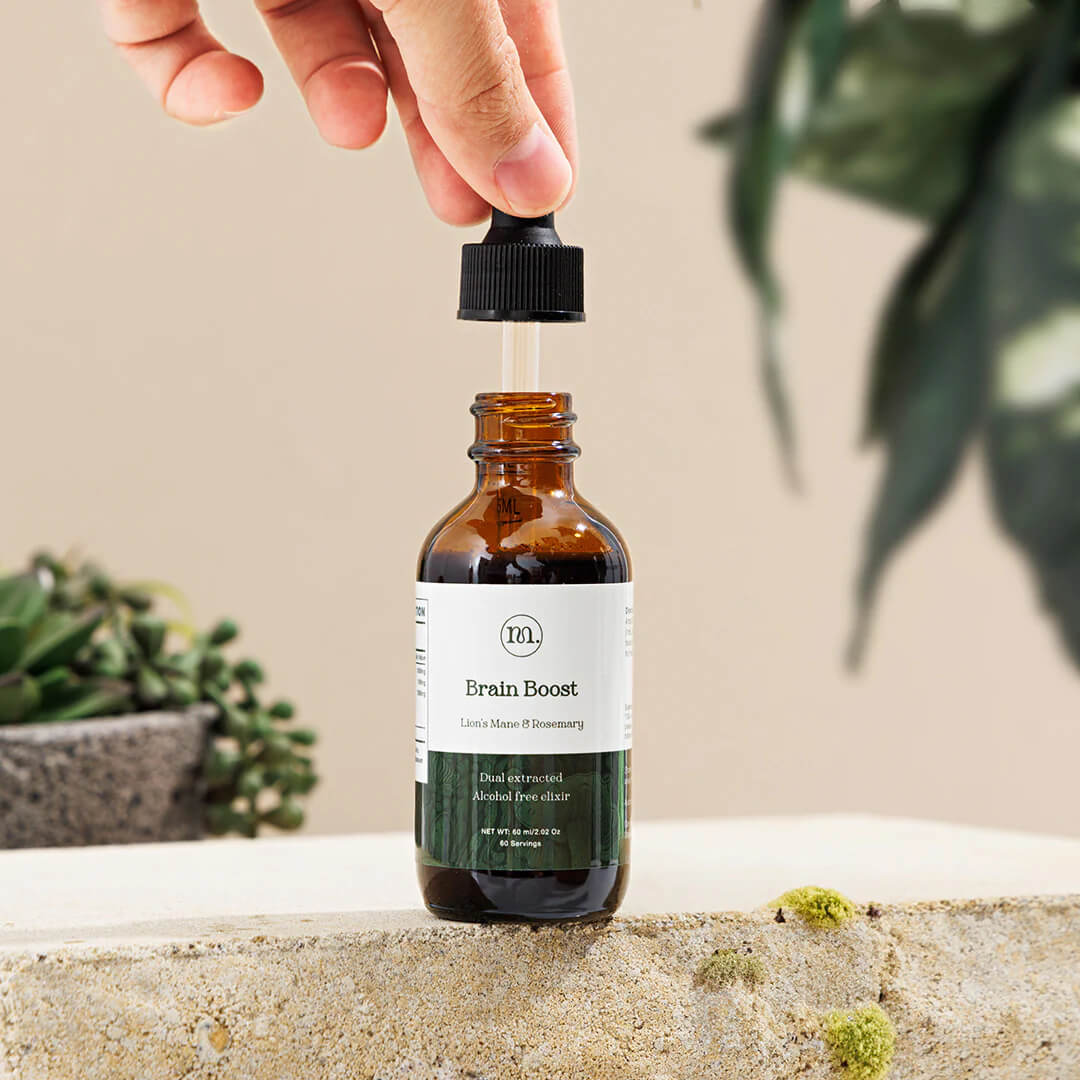 Bottle labeled 'Brain Boost' with a dropper being used, against a neutral background with plants.