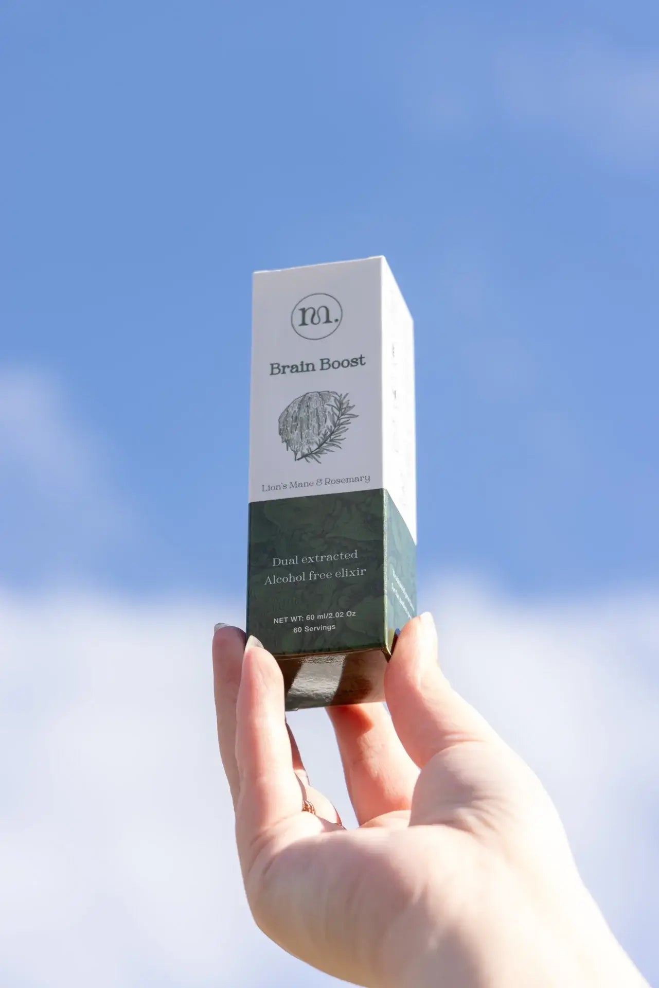 Hand holding a 'Brain Boost' supplement box against a blue sky